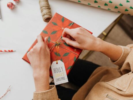 https://www.pexels.com/photo/person-tying-a-gold-ribbon-on-red-and-green-box-5979435/