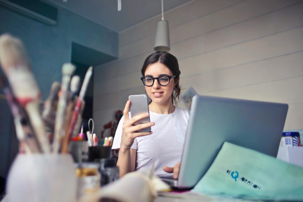 https://www.pexels.com/photo/woman-in-white-t-shirt-holding-smartphone-in-front-of-laptop-914931/