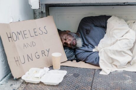 https://www.pexels.com/photo/photo-of-a-homeless-man-sleeping-near-a-cardboard-sign-9532305/