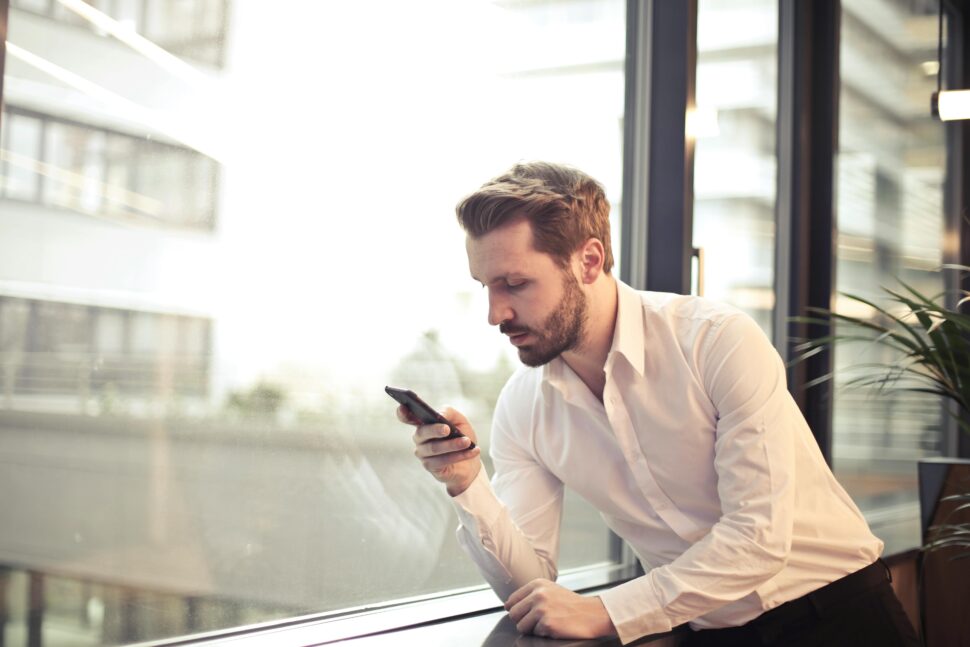 https://www.pexels.com/photo/photo-of-man-in-white-dress-shirt-holding-phone-near-window-859265/