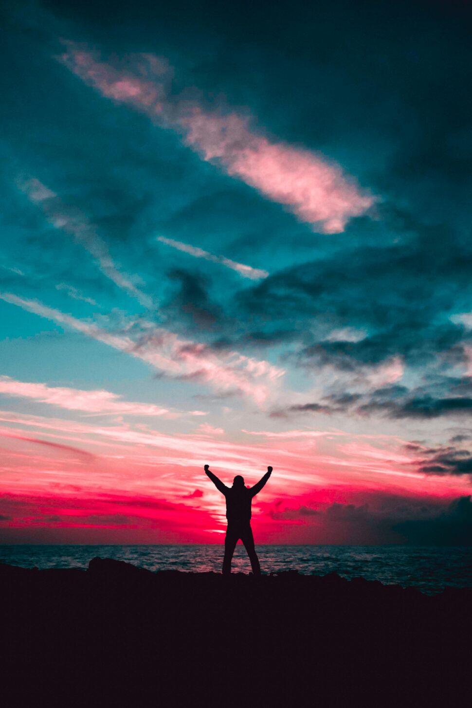 https://www.pexels.com/photo/silhouette-of-man-raising-hands-against-a-red-sunset-light-under-green-clouds-801885/
